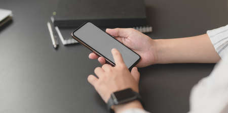 Close-up view of young professional businesswoman holding blank screen smartphone in her office roomの写真素材