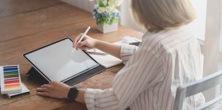Cropped shot of young professional designer drawing on her project with blank screen tablet in comfortable workspaceの写真素材