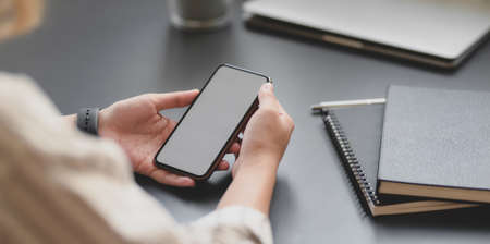 Close-up view of young professional businesswoman holding blank screen smartphone in her office roomの写真素材