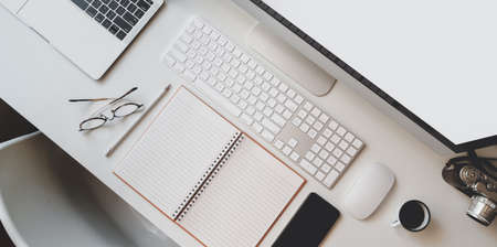 Cropped shot of modern workplace with open blank notebook, keyboard computer and desktop computer with office suppliesの写真素材