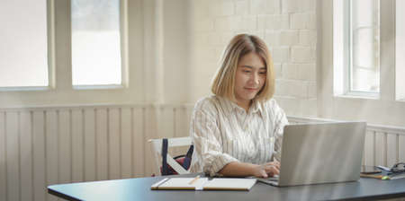 Young beautiful business woman typing on laptop computer in comfortable workplaceの写真素材