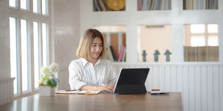 Portrait of young female professional designer working on her project with  tablet in her comfortable workplaceの写真素材