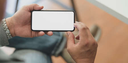 Cropped shot of professional businessman holding horizontal blank screen smartphone in his office roomの写真素材