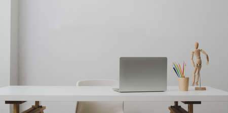 Laptop computer on white table and coffee cup in modern office room with white wall backgroundの写真素材