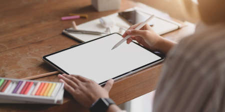 Cropped shot of young professional female designer working on blank screen tablet in her workspace with office suppliesの写真素材