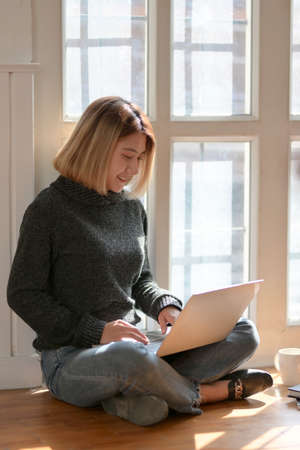 Young professional freelancer working on her project while sitting near the windows at her workplaceの写真素材