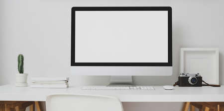 Modern workspace with blank screen desktop computer and decorations on white table and white wall backgroundの写真素材