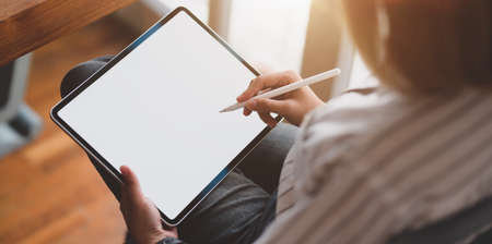 Close-up view of young female designer working on blank screen tablet in her workspaceの写真素材