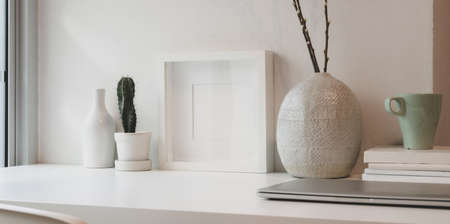 Blank white frame and ceramics jar on a white table against the white wall with copy spaceの写真素材
