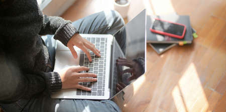 Close-up view of young female freelancer working on her project with laptop computer while sitting near the windowsの写真素材