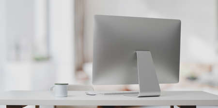 Desktop computer on white table and coffee cup in modern office room with blurred backgroundの写真素材