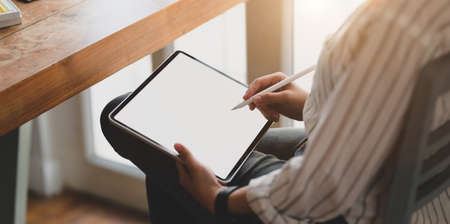 Close-up view of young female designer working on blank screen tablet in her workspace