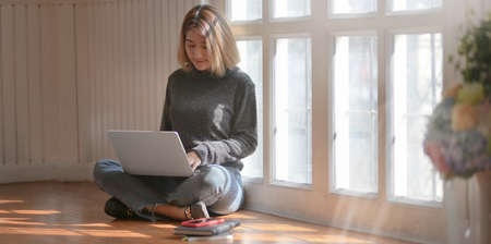 Young professional freelancer working on her project while sitting near the windows at her workplaceの写真素材