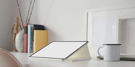 Blank screen tablet in white minimal workspace with office supplies and mock up frame on white tableの写真素材