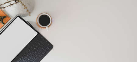 Top view of modern workspace with digital tablet, keyboard, smartphone and coffee cup on white tableの写真素材