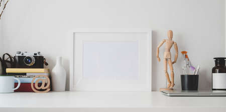 Minimal workspace with mock up frame and office supplies on white wooden table and white wall backgroundの写真素材