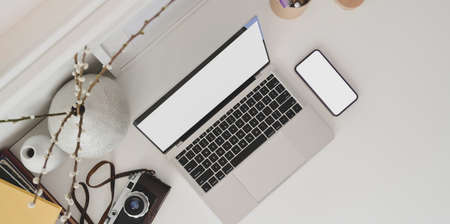 Top view of minimal workplace with laptop computer, camera and office supplies on white deskの写真素材