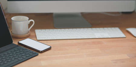 Cropped shot of modern workspace with office supplies and desktop computer on wooden table