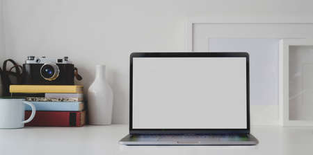 Open blank screen laptop computer in minimal workplace with camera and office supplies
