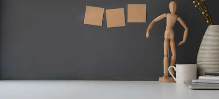Minimal workspace with copy space and decorations on white table and dark grey wall background の写真素材