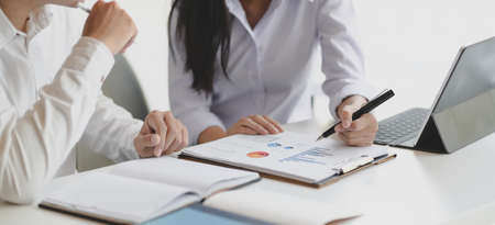 Cropped shot of two professional business partner discussing their project together while using graphs and charts の写真素材