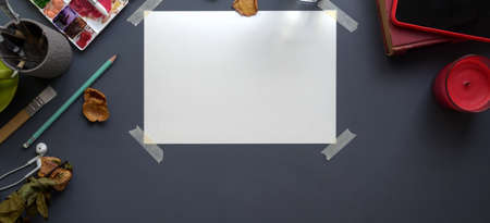 Top view of professional artist workspace with sketch paper, painting tools and office supplies on dark grey desk backgroundの写真素材