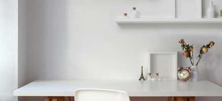 Minimal workplace with copy space and decorations on white table with white wall background の写真素材