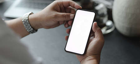 Cropped shot of businessman looking at his mock up smartphone while working on his projectの写真素材