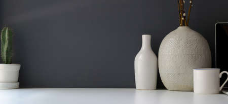Modern workspace with copy space and ceramic vase on white table and grey wall background の写真素材