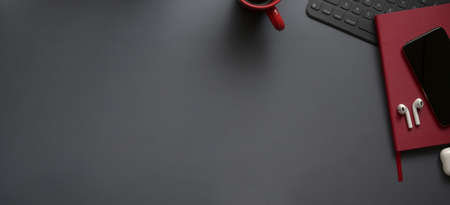 Overhead shot of dark luxury workspace with red notebooks and copy space with office supplies on grey desk background の写真素材