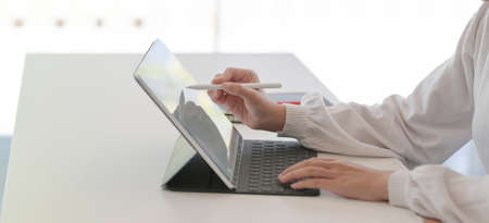 Cropped shot of young businesswoman working on her project while using tablet in modern office room