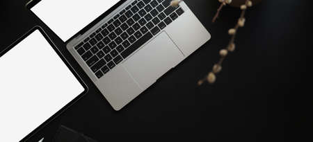 Top view of dark modern workspace with mock up laptop computer and tablet on black leather desk の写真素材