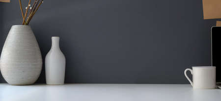 Modern workspace with copy space and ceramic vase on white table and grey wall background の写真素材