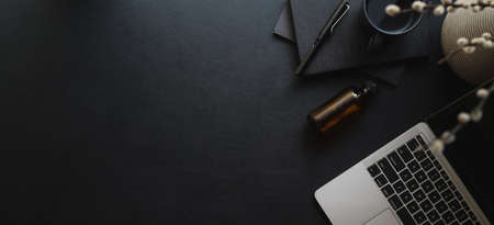 Overhead shot of dark modern workspace wit laptop computer and copy space with office supplies on black leather desk の写真素材
