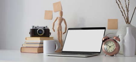 Contemporary workplace with open blank screen laptop computer, office supplies and decorations on white table の写真素材