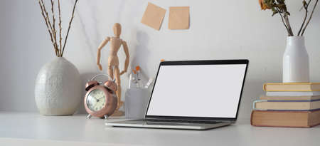 Contemporary workplace with open blank screen laptop computer, office supplies and decorations on white table の写真素材