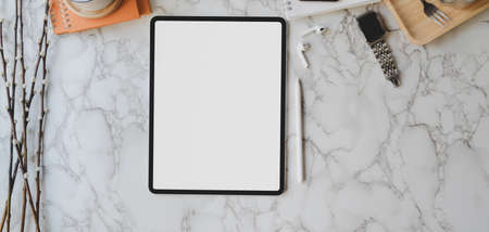 Overhead shot of trendy workspace with digital tablet and office supplies on marble desk background