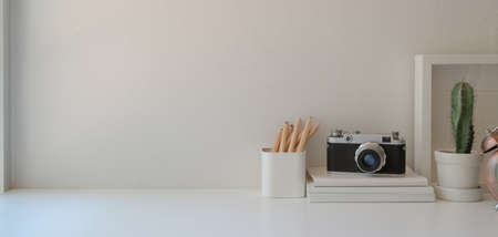 Minimal workplace with copy space and office supplies on white wooden table and white wall backgroundの写真素材