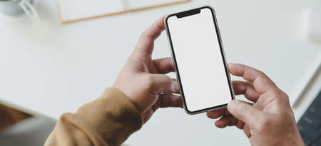 Cropped shot of young man searching information in his blank screen smartphoneの写真素材