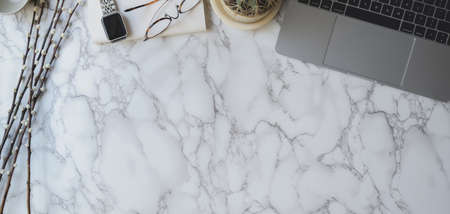 Overhead shot of stylish workspace with laptop computer, smartphone and office supplies on marble...