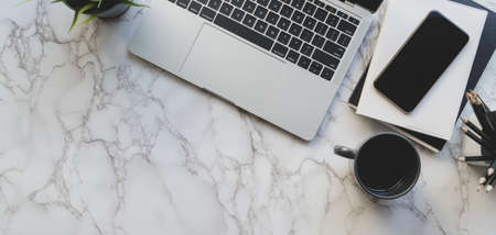 Top view of stylish workspace with laptop computer and office supplies on marble desk background 