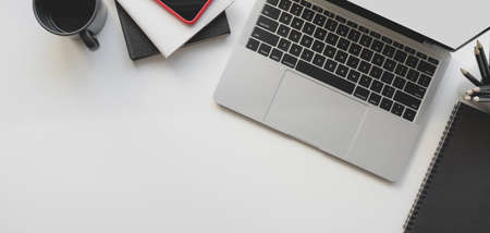 Top view of modern workspace with laptop computer and office supplies on white table background