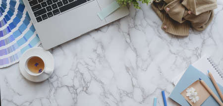 Overhead shot of light blue feminine designer workspace with laptop computer and painting tools on marble desk background の写真素材