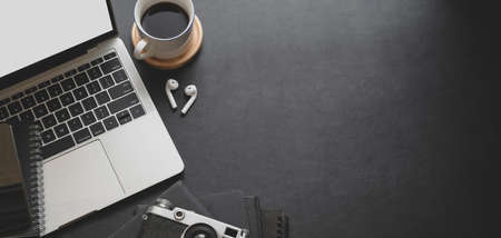 Close-up view of dark modern workplace with laptop computer and office supplies on black table backgroundの写真素材
