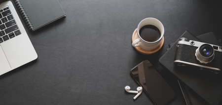 Close-up view of dark trendy workspace with laptop computer, coffee cup and office supplies with copy spaceの写真素材