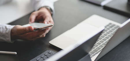 Close-up view of young professional businessman using smartphone while working on his projectの写真素材