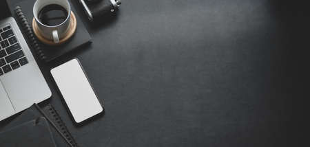 Top view of dark modern workplace with mock up smartphone and office supplies with copy space on black table backgroundの写真素材