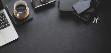Top view of dark trendy workspace with laptop computer, coffee cup and office supplies with copy spaceの写真素材