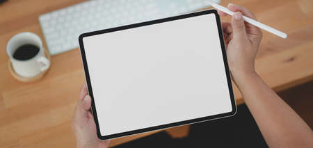 Cropped shot of young man holding blank screen tablet in his comfortable workspaceの写真素材