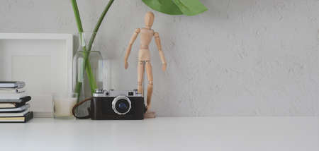 Minimal workplace with mock up frame, camera and office supplies on white table backgroundの写真素材